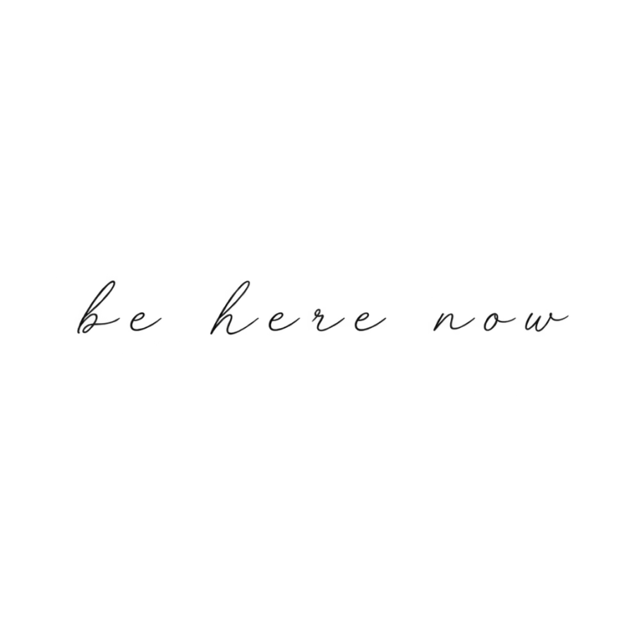 Cursive tattoo lettering of be here now in light widely spaced script